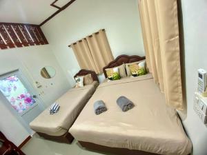 two twin beds in a room with a window at บ้านคุณโต้ง เชียงคาน BaanKhunTong ChiangKhan in Chiang Khan