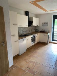 una cucina con armadietti bianchi e pavimento piastrellato di Ferienwohnung auf dem Gutshof Renz a Weissenfels Altre 7 foto