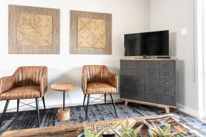 two chairs in a living room with a tv and a dresser at Avemore Jan Cats No 3 full back up power in Stellenbosch