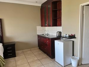 Una cocina con un refrigerador blanco y gabinetes marrones. en Boat Yard Guest House, en Hartbeespoort