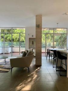 - un salon avec un canapé, des tables et des fenêtres dans l'établissement Renovated penthouse near Hayarkon Park - 3 bedroom, à Tel Aviv