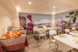 a restaurant with white tables and chairs and a painting at Profumi di Primavera Luxury Rooms & Suite in Matera