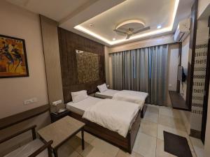 a hotel room with two beds and a tv at Kishori Vatika in Rāmnagar
