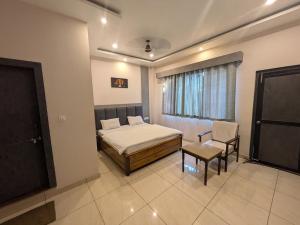a bedroom with a bed and a chair and a window at Kishori Vatika in Rāmnagar +10 photos