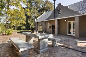ステレンボッシュにあるAvemore Winelands Home - wood fired hottub and full power back upの家の前のピクニックテーブルとベンチ