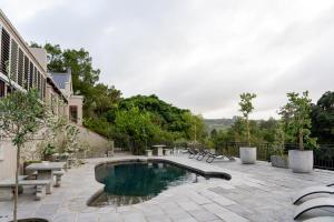 a swimming pool with benches and a patio with at Avemore Vineyard View - wood fired hot tub and full power back up in Onder-Papegaaiberg
