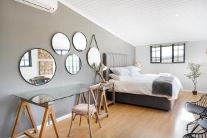 a bedroom with a bed and a table and mirrors at Avemore Vineyard View Le Verger in Onder-Papegaaiberg +40 photos