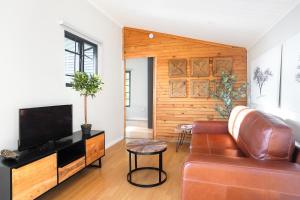 a living room with a couch and a television at Avemore Vineyard View - wood fired hot tub and full power back up in Onder-Papegaaiberg