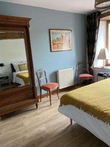 a bedroom with a bed and a mirror and chairs at Les Pommiers d'Amfreville, Chambres d'hôtes & Table d'hôtes in Picauville