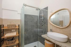 une salle de bain avec un lavabo et une douche avec un miroir dans l'établissement I ricami di Annina, à Castellana Grotte