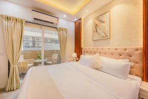 a bedroom with a large white bed and a window at Kyomi Service Apartments in Gurgaon
