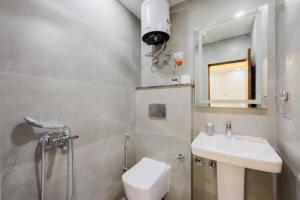 a bathroom with a sink and a toilet and a mirror at Kyomi Service Apartments in Gurgaon
