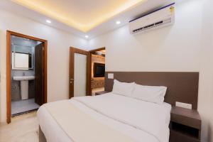 a bedroom with a white bed and a bathroom at Kyomi Service Apartments in Gurgaon