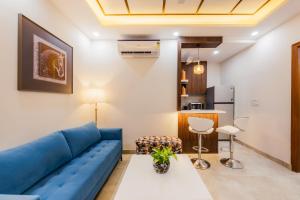 a living room with a blue couch and a table at Kyomi Service Apartments in Gurgaon