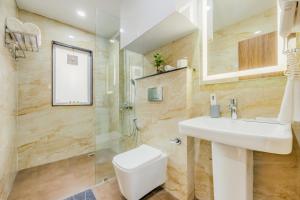 a bathroom with a white sink and a toilet at Kyomi Service Apartments in Gurgaon