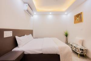 a bedroom with a white bed and a chair at Kyomi Service Apartments in Gurgaon