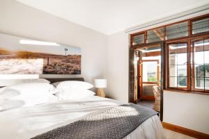 una camera da letto bianca con un letto grande e una finestra di Avemore Manor House wood fired hot tub magical views and full Backup power a Stellenbosch