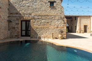 a swimming pool in front of a stone building at Tenute Baglio Passofondo in Alcamo