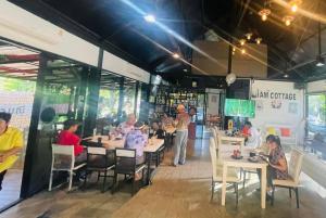 un gruppo di persone sedute ai tavoli di un ristorante di I AM Cottage เฮือนแก้วมณี a Nakhon Pathom