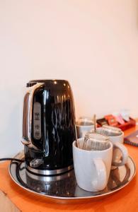 a coffee maker on a tray with cups on a table at The Grand Hotel & Bar - Akaroa in Akaroa