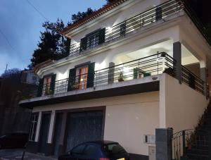 ein weißes Haus mit einem Balkon und einem Auto vor dem Haus in der Unterkunft Madeira house garden Villa in Estreito de Câmara de Lobos