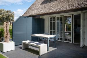 eine Terrasse mit einem Tisch und einer Bank sowie ein Haus in der Unterkunft Beach Lodge Beach Lodge Appartement 6 in Sankt Peter-Ording