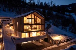 una casa è illuminata nella neve di notte di Bear & Bison Lake View a Zell am See
