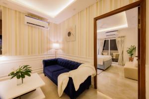 a living room with a blue couch and a mirror at Kyomi Service Apartments in Gurgaon
