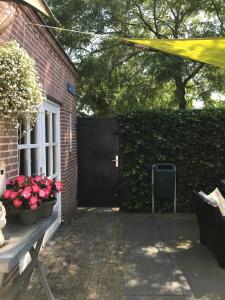 a black door to a brick building with pink flowers at Villa Pats in Gilze