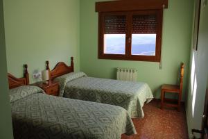 a room with two beds and a window at Pension Los Mallos in Riglos
