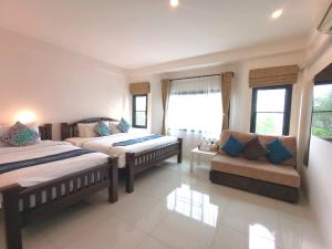 una camera con due letti e un divano in camera di SASIMA Bed and Breakfast a Chiang Mai