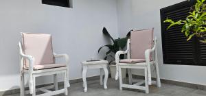 two pink chairs and a side table on a porch at Alunita & Pirita Rooms - Peaceful Private Rooms with Garden, Terrace & Shared Kitchen in Nazaret