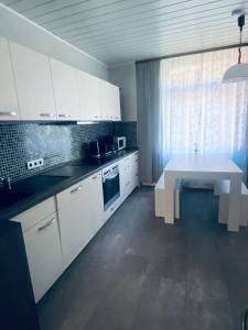 a kitchen with white cabinets and a white table at 1923 Wohnung by Gerda in Etgersleben +7 photos
