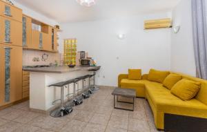 a living room with a yellow couch and a kitchen at Apartman ALEN in Klanice Dobrinj