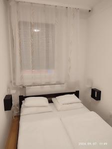 a bed with two pillows in a room with a window at LBB apartman in Sátoraljaújhely