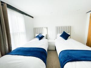 two beds in a room with blue pillows at Chelmsford City - 17th Century Apartment in Chelmsford