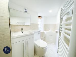 a white bathroom with a toilet and a sink at Chelmsford City - 17th Century Apartment in Chelmsford
