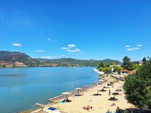a beach with umbrellas and people on the sand and water at Apartman Misic in Donji Milanovac