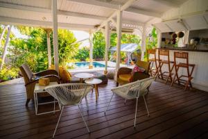 a porch with chairs and a table and a pool at Villa Le Ropert'Zen in Saint-François