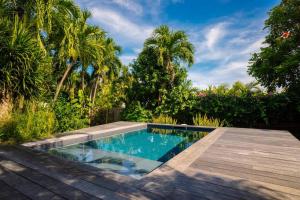 a swimming pool in a garden with a wooden deck at Villa Le Ropert'Zen in Saint-François