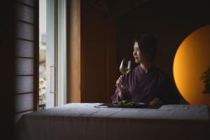 una mujer sentada en una mesa con una copa de vino en 結びの小宿 縁 by Wellbe, en Kobe