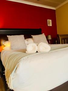 a bed with two white pillows and a red wall at Mondeor Homestay in Johannesburg