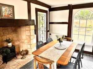 une salle à manger avec une table et une cheminée dans l'établissement Stylish Tudor Cottage & Hot Tub, à Coombe Hill