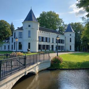 un grande edificio bianco con un ponte sul fiume di Bed & Breakfast Puur Natuur Putten, met privé sauna a Putten