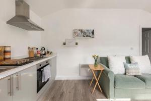 a living room with a green couch in a kitchen at Ty Cwtch in Nottage +7 photos