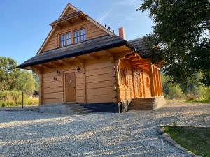 a wooden cabin with a door on a gravel road at Chata Hyrlata 2 in Cisna