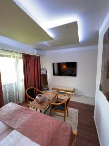 ein Wohnzimmer mit Tisch und Stühlen und einem Fernseher in der Unterkunft Soba sa kupaonom i balkonom Aman in Bihać