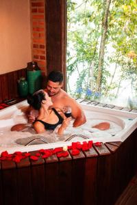 a man and woman in a bathtub with a glass of wine at Chalés Senhor Dos Trilhos in Mairiporã +153 photos