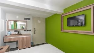 a bathroom with a green wall with a television on it at Zeytin HOTEL in Kaş