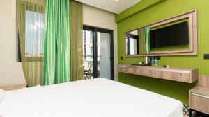 a bedroom with a bed and a tv on a green wall at Zeytin HOTEL in Kaş